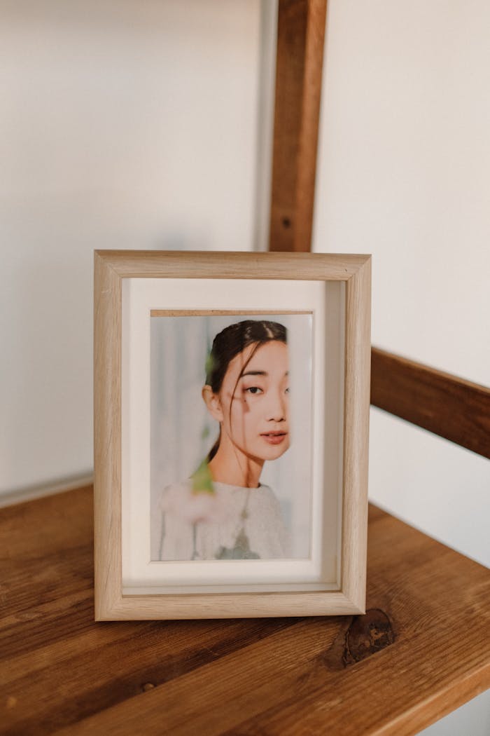 Elegant framed portrait of a woman displayed on a wooden shelf indoors.